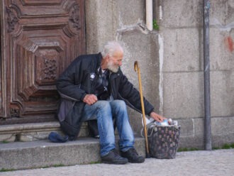 Alter Mann sitzt auf einer Treppe und wühlt im Abfall