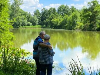 Ein älteres Ehepaar hält sich an einem See