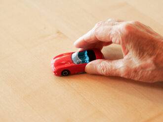 Alter Mensch spielt mit Spielzeugauto