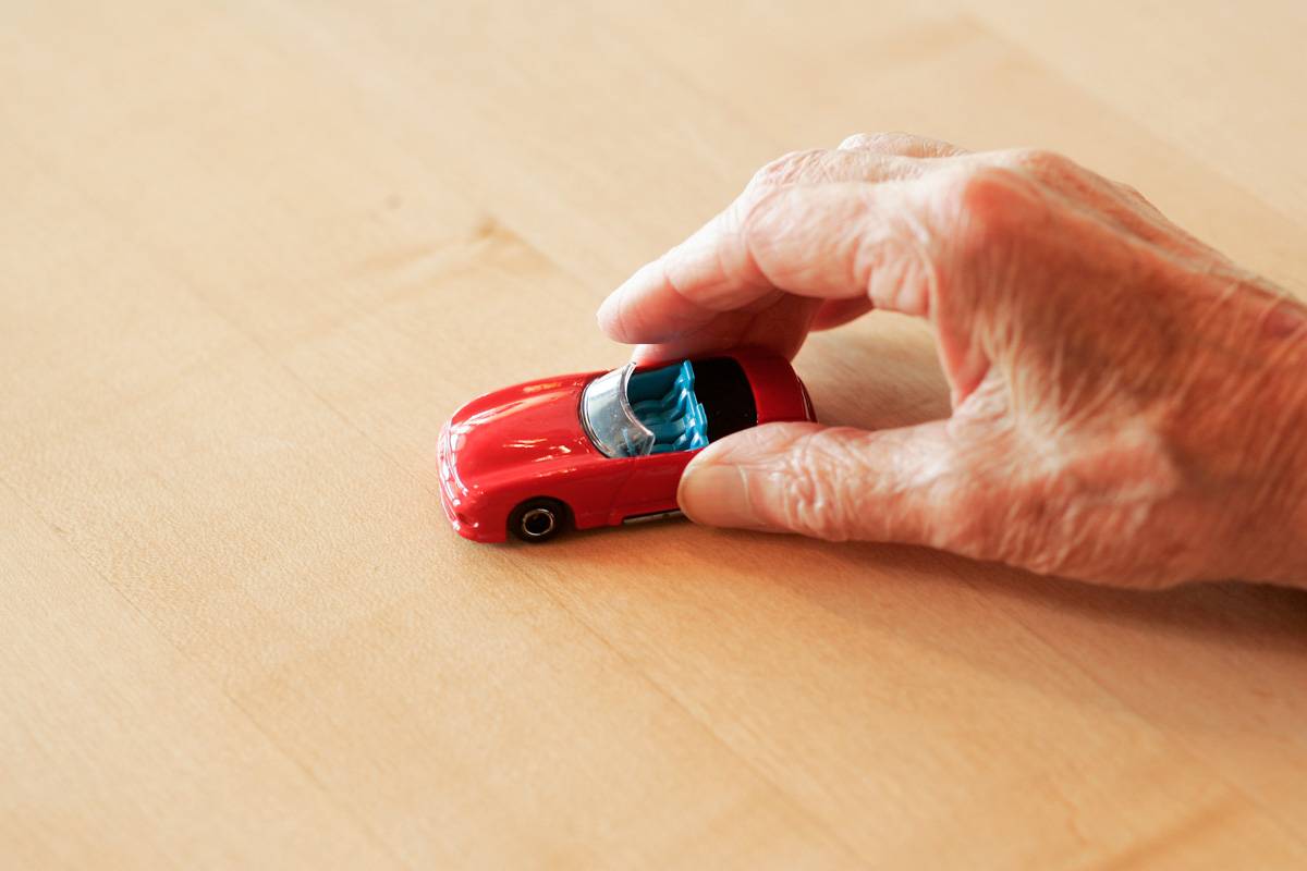 Alter Mensch spielt mit Spielzeugauto