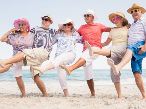 Alte Menschen tanzen am Strand und lachen.