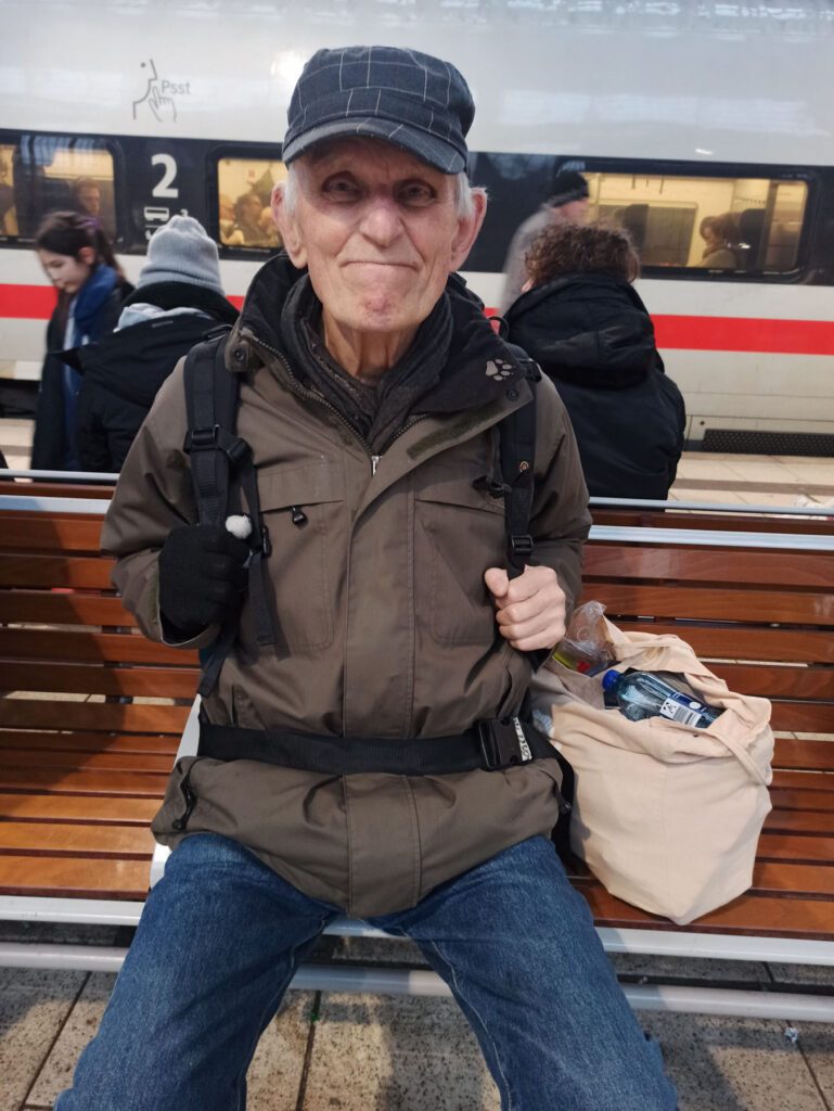 Otmar Hoffmann sitzt auf einer Bank am Bahnhof.